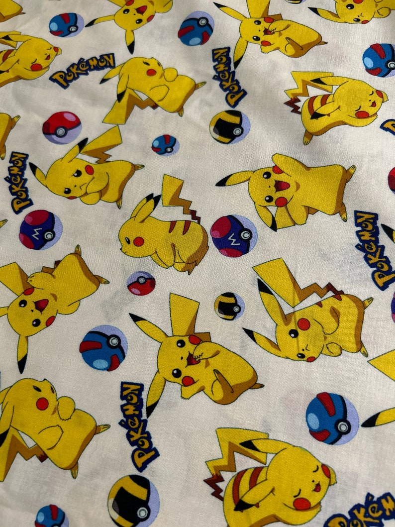 May include: White fabric patterned with yellow Pikachu characters, red and white Pok&eacute; Balls, and blue and black Pok&eacute; Balls. The word "Pokemon" is printed in blue.
