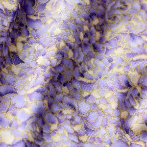May include: Purple fabric with a white and gold floral pattern. The fabric has a textured surface.