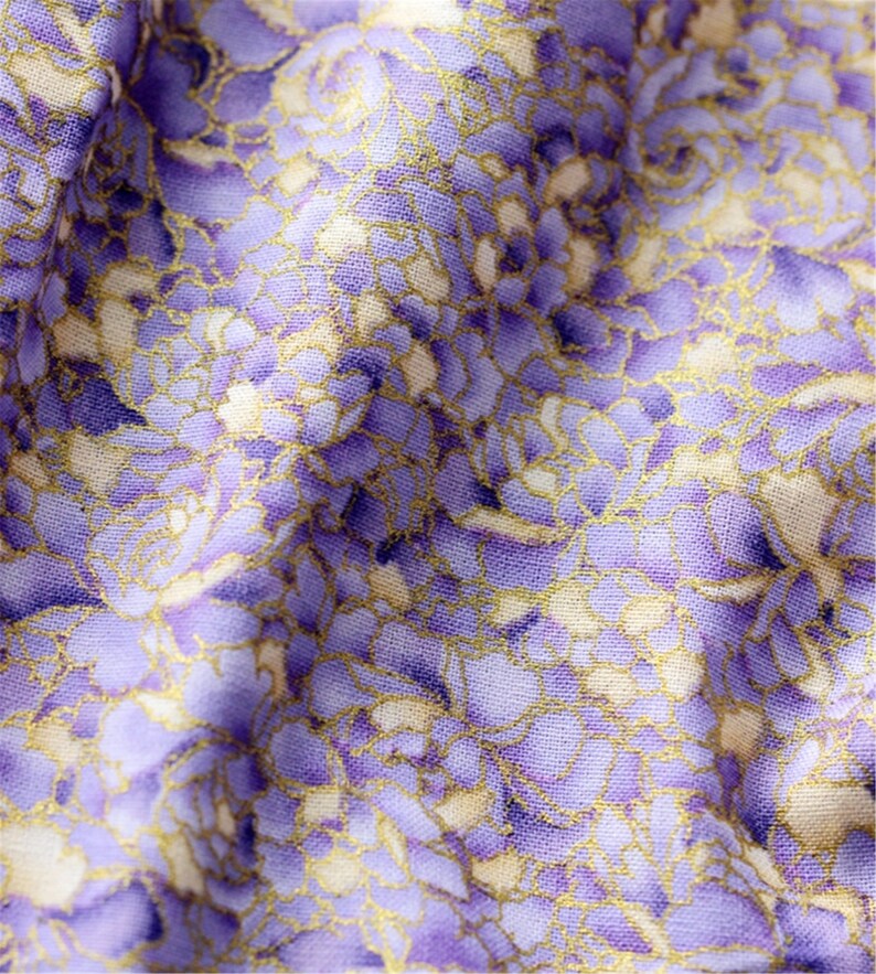 May include: Purple fabric with a white and gold floral pattern. The fabric has a textured surface.