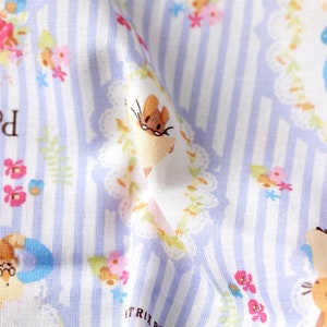 May include: A white fabric with a light blue and white striped pattern. The fabric features a repeating pattern of small flowers, leaves, and mice wearing glasses. The text " Beatrix Potter" is visible in the bottom right corner.