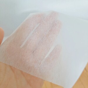 May include: A white, thin, textured sheet of fabric. The fabric is translucent and has a slightly rough texture.