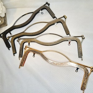 May include: Four different metal purse frames, two in silver, one in gold, and one in black. The frames are all in a curved shape and have a decorative design.