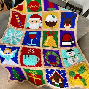 May include: A crocheted Christmas blanket featuring a range of festive designs, including Santa Claus, a snowman, a Christmas tree, and a gingerbread house.