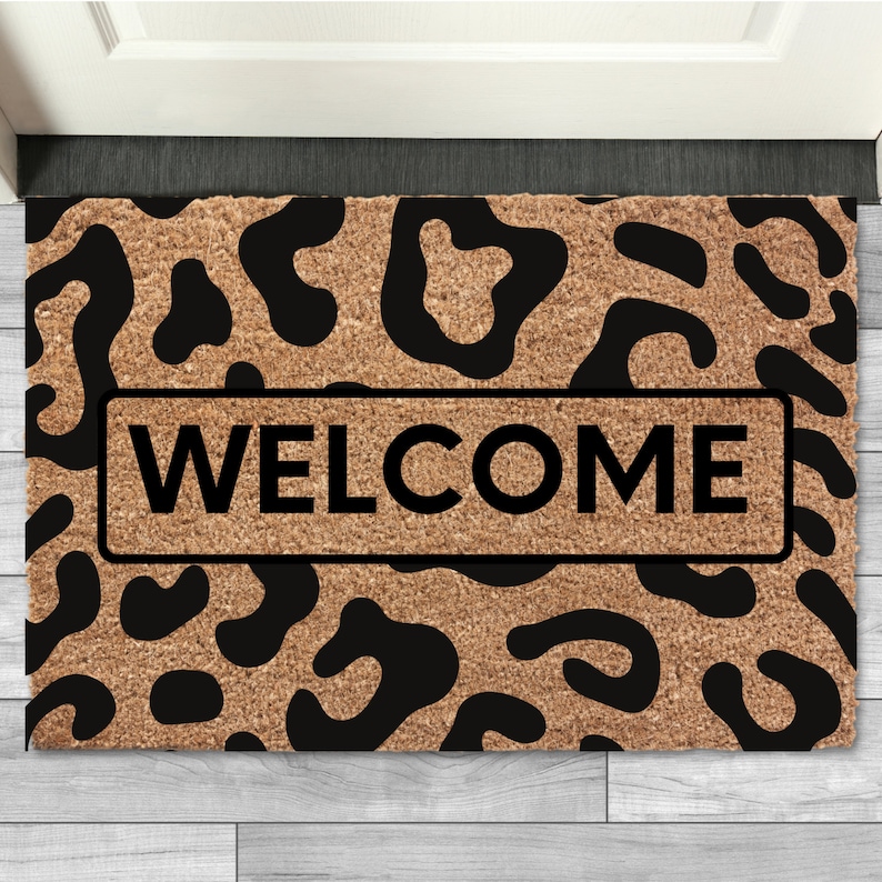 May include: A brown doormat with a black leopard print design and the word "WELCOME" in black text.