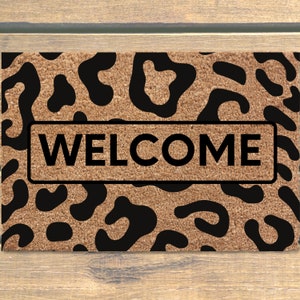 May include: A brown doormat with a black leopard print design and the word "WELCOME" in black text.