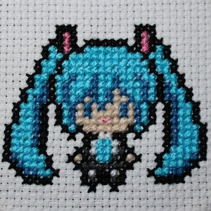 May include: Cross-stitch of a cartoon character with long, turquoise hair and black accents. The character has a light skin tone, pink lips, and is wearing a black outfit with a turquoise bow. The cross-stitch is on a white fabric background.