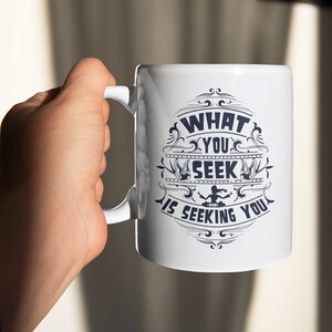 May include: White ceramic mug with a blue design that says "What you seek is seeking you".