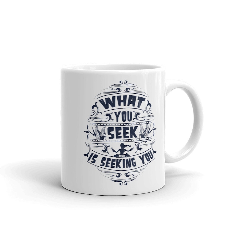 May include: White ceramic coffee mug with a blue design that says "What you seek is seeking you".