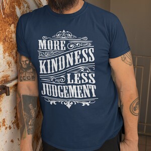 May include: A navy blue t-shirt with a white graphic design that reads "More Kindness Less Judgement" in a vintage style font.
