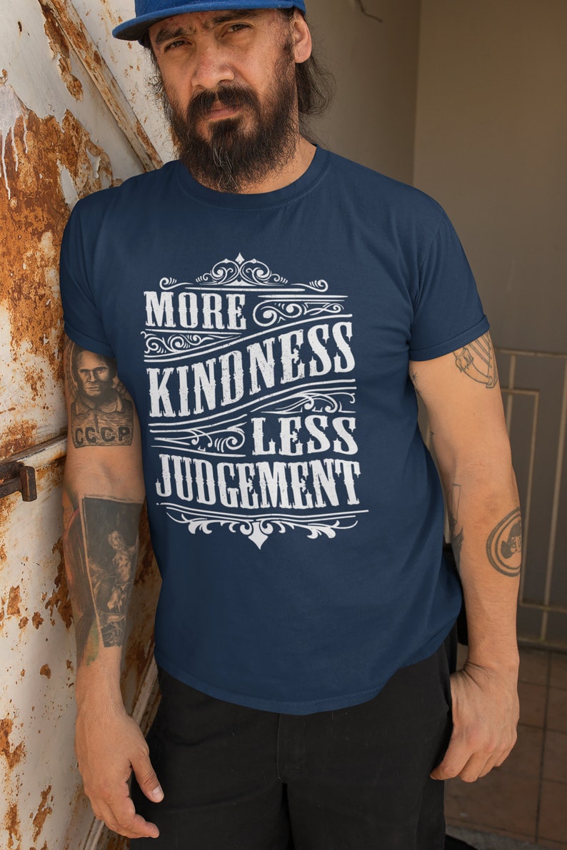 May include: A navy blue t-shirt with a white graphic design that reads "More Kindness Less Judgement" in a vintage style font.
