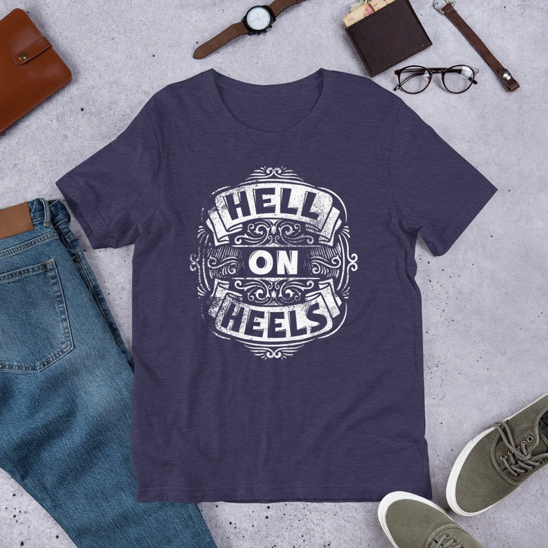 May include: A navy blue t-shirt with a white distressed graphic that says "Hell on Wheels" in a vintage style font.