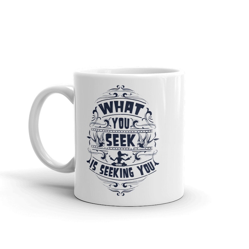 May include: White ceramic coffee mug with a blue design that says "What you seek is seeking you".