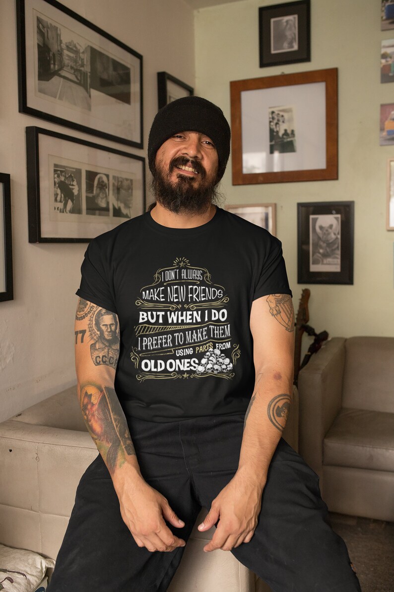 May include: A black t-shirt with a graphic print that reads "I don't always make new friends, but when I do I prefer to make them using parts from old ones". The graphic is surrounded by a decorative border and includes a skull design.