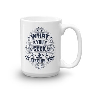 May include: White ceramic coffee mug with a blue design that says "What you seek is seeking you - Rumi".