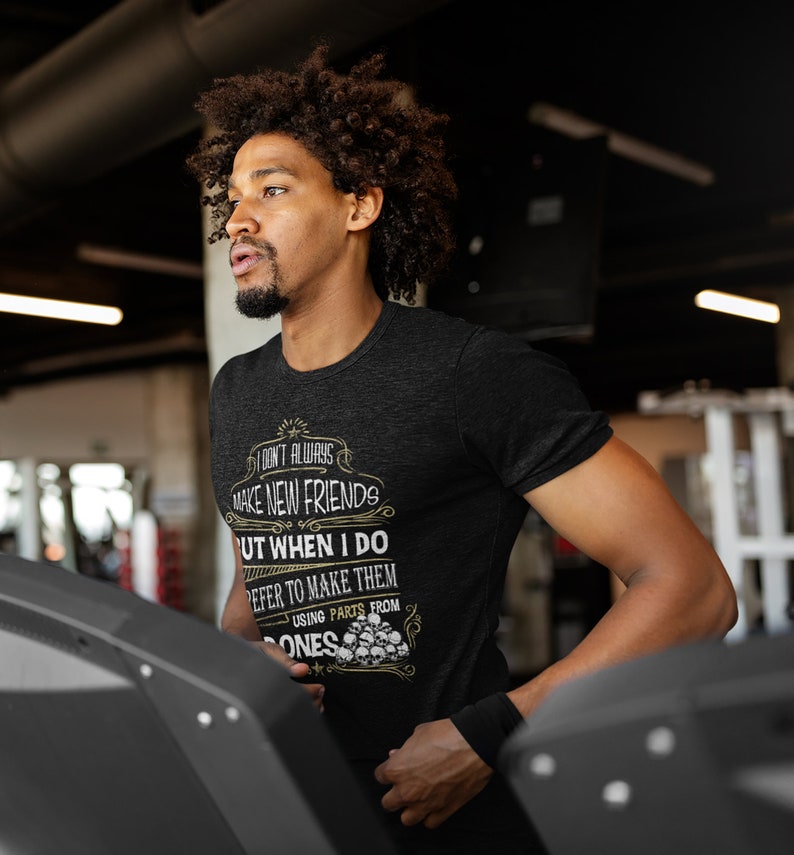 May include: A black t-shirt with a white graphic print that says "I don't always make new friends but when I do I prefer to make them using parts from bones". The graphic is surrounded by a decorative border and includes a skull and crossbones design.