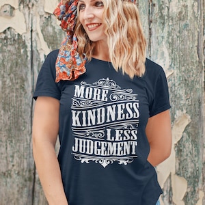 May include: A navy blue t-shirt with a white vintage-style graphic that reads "More Kindness Less Judgement".