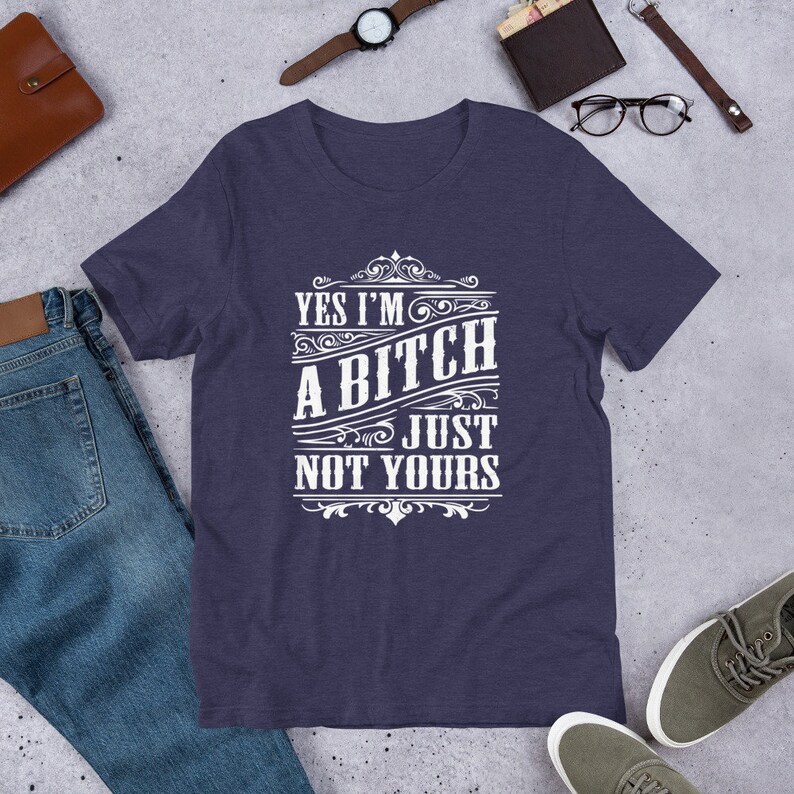 May include: A navy blue t-shirt with a white graphic that says "Yes I'm a Bitch Just Not Yours" in a vintage style font.