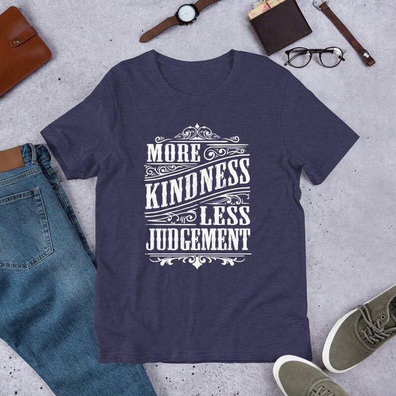 May include: A navy blue t-shirt with a white vintage-style graphic that reads "More Kindness Less Judgement".