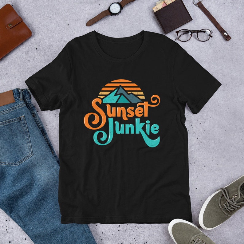 May include: Black t-shirt with a graphic of a sunset over mountains and the text "Sunset Junkie" in a retro font.