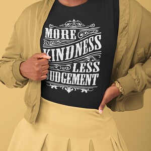 May include: A black t-shirt with a white vintage-style graphic that reads "More Kindness Less Judgement".