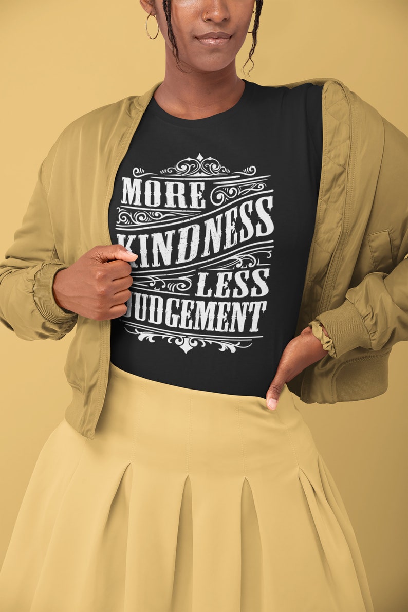 May include: A black t-shirt with a white vintage-style graphic that reads "More Kindness Less Judgement".