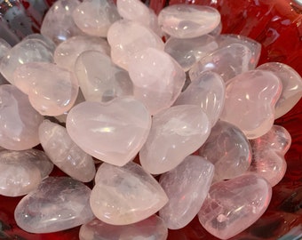 May include: A bowl filled with many small, heart-shaped, pale pink rose quartz crystals.
