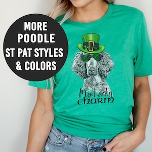 Pu&ograve; includere: Una maglietta verde con un barboncino bianco e nero che indossa un cappello verde da folletto e occhiali da sole. Il testo "My Lucky Charm" &egrave; stampato sulla maglietta.