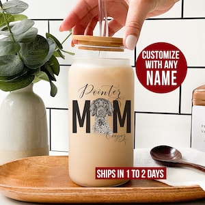 May include: A clear glass jar with a bamboo lid and straw. The jar has a black and white graphic of a German Shorthaired Pointer dog with the text "Pointer Mom" and the name "Cooper" underneath. The jar is sitting on a wooden surface.