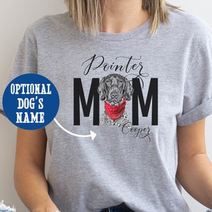 May include: A gray t-shirt with the words "Pointer MOM" in black block letters. A watercolor illustration of a German Shorthaired Pointer wearing a red bandana is in the center. The dog's name, "Cooper," is written below. A blue circle with the text "OPTIONAL DOG'S NAME" is on the left.