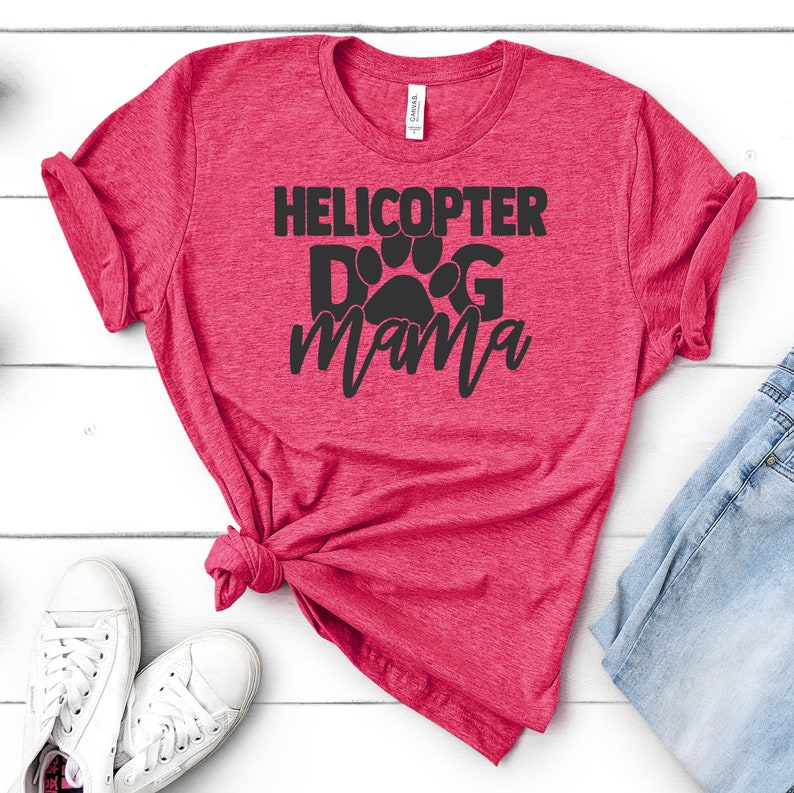May include: A red t-shirt with the text "Helicopter Dog Mama" in black lettering with a paw print in the middle of the word "Dog".