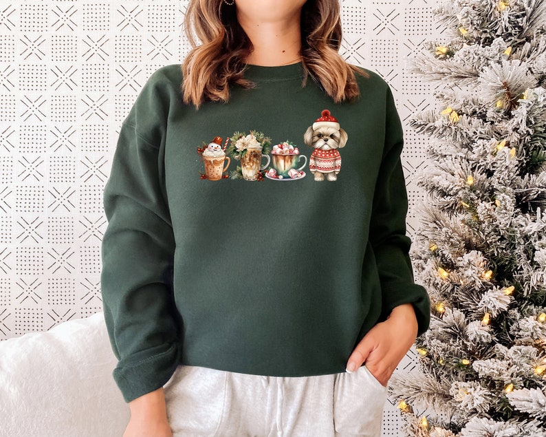 May include: A dark green sweatshirt with a festive design featuring a dog wearing a Santa hat and four mugs of hot chocolate with whipped cream and candy canes.