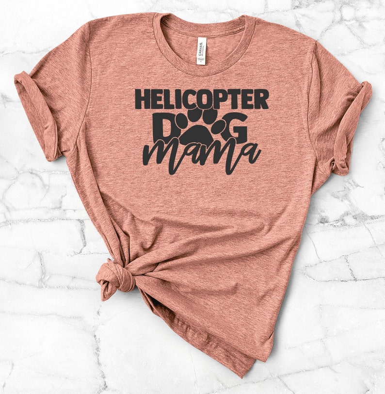 May include: A heather brown t-shirt with the text "Helicopter Dog Mama" in black lettering. The text includes a paw print graphic.