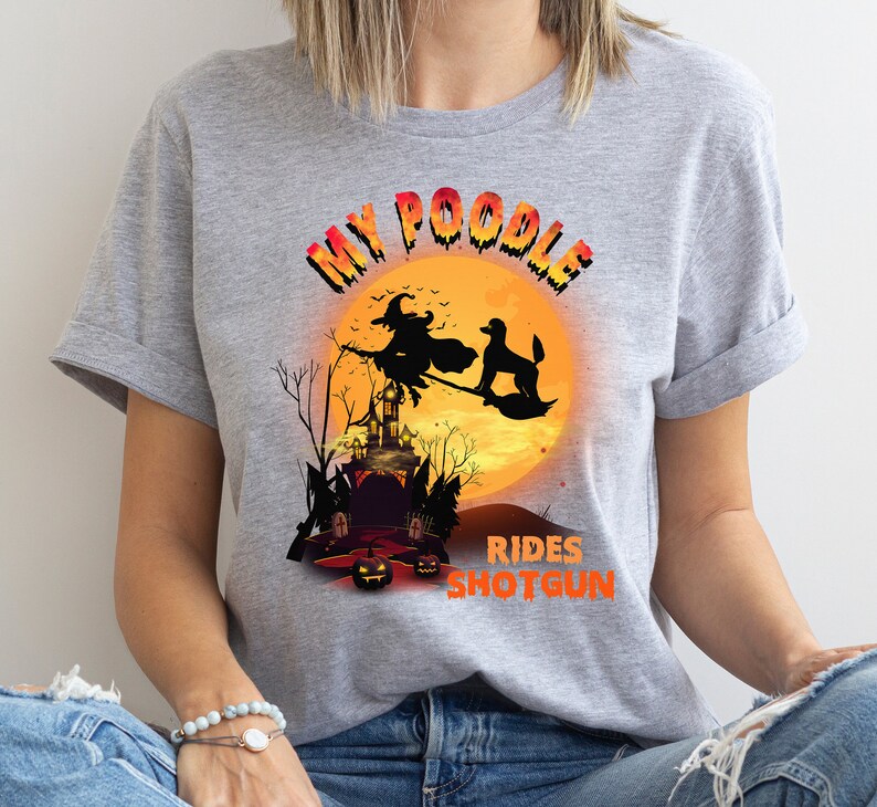 May include: Gray t-shirt with a graphic of a poodle riding a broomstick with a witch in front of a full moon and a haunted house. The text reads "My Poodle Rides Shotgun".