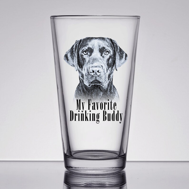 May include: A clear glass pint glass with a black Labrador Retriever dog illustration and the text "My Favorite Drinking Buddy".