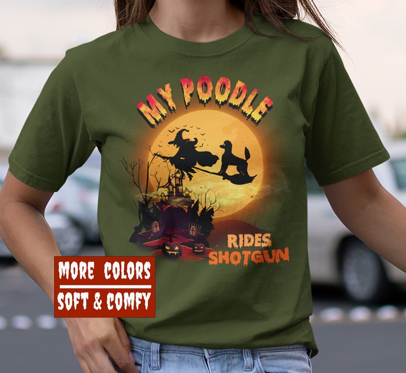 May include: A green t-shirt with the text "My Poodle Rides Shotgun" in white and orange. The design features a witch flying on a broomstick with a poodle in front of a full moon and a haunted house.