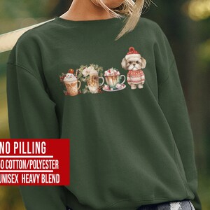 May include: A dark green sweatshirt with a festive design featuring a dog wearing a Santa hat and surrounded by hot chocolate and marshmallows. The text "NO PILLING 50/50 COTTON/POLYESTER 8 OZ.UNISEX HEAVY BLEND" is printed on the bottom of the sweatshirt.