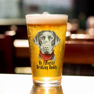 May include: A clear glass beer mug with a black Labrador Retriever wearing a red bandana printed on the side. The text "My Favorite Drinking Buddy" is printed below the dog.