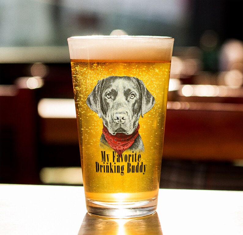 May include: A clear glass beer mug with a black Labrador Retriever wearing a red bandana printed on the side. The text "My Favorite Drinking Buddy" is printed below the dog.