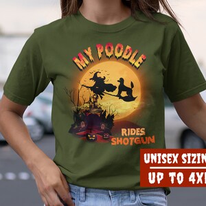 May include: Green t-shirt with a graphic of a witch riding a broom with a poodle in front of a full moon. The text "My Poodle Rides Shotgun" is printed on the shirt. Unisex sizing up to 4XL.