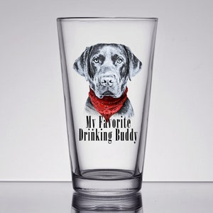 May include: A black and white illustration of a black labrador wearing a red bandana on a clear glass pint glass. The text "My Favorite Drinking Buddy" is printed on the glass.
