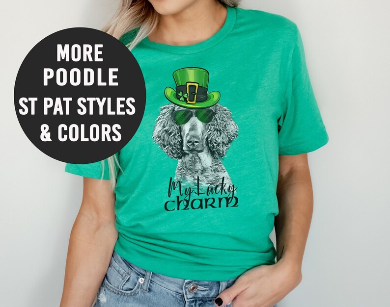 Pu&ograve; includere: Una maglietta verde con un barboncino bianco e nero che indossa un cappello verde da folletto e occhiali da sole. Il testo "My Lucky Charm" &egrave; stampato sulla maglietta.
