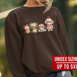 May include: A brown sweatshirt with a graphic of a dog wearing a Santa hat and holding a cup of hot chocolate. The graphic also includes other cups of hot chocolate and a snowman. The sweatshirt has the text "Unisex Sizing Up to 5XL" printed on the bottom right corner.