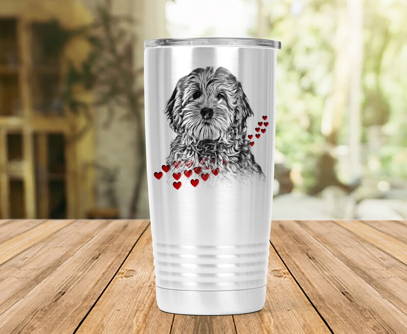 May include: A white insulated travel mug with a black and white dog illustration and red heart accents. The mug has a silver lid and a ridged design near the base. The dog illustration is detailed and centered on the mug. The mug is designed to keep drinks hot or cold.