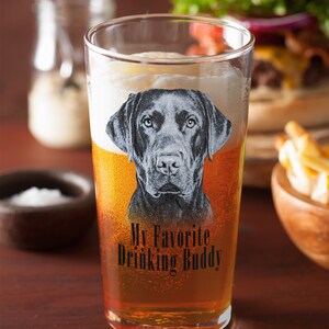 May include: A clear glass beer mug with a black Labrador Retriever image and the text "My Favorite Drinking Buddy".