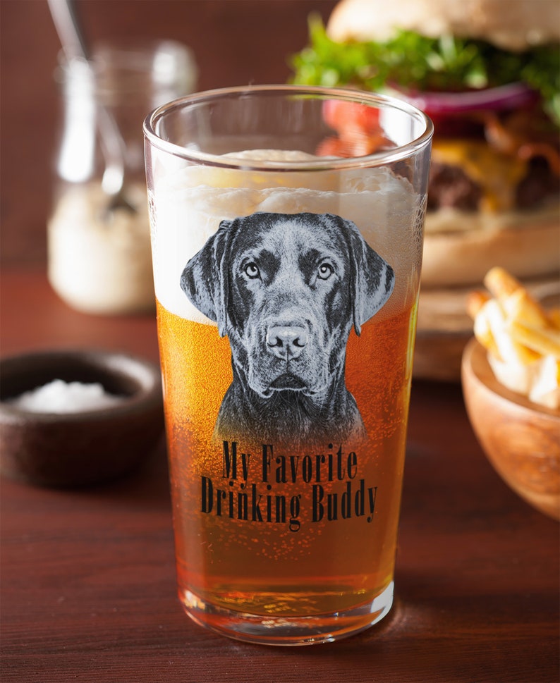 May include: A clear glass beer mug with a black Labrador Retriever image and the text "My Favorite Drinking Buddy".