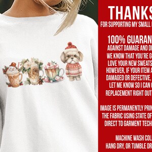 May include: White sweatshirt with a Christmas-themed design featuring a snowman, hot chocolate, and a dog wearing a red and white sweater. The text "THANKS FOR SUPPORTING MY SMALL BUSINESS! 100% GUARANTEE AGAINST DAMAGE AND DEFECTS. WE KNOW THAT YOU'RE GOING TO LOVE YOUR NEW SWEATSHIRT! HOWEVER, IF YOUR ITEM ARRIVES DAMAGED OR DEFECTIVE, PLEASE LET ME KNOW SO I CAN GET A REPLACEMENT RIGHT OUT TO YOU. IMAGE IS PERMANENTLY PRINTED INTO THE FABRIC USING STATE OF THE ART DIRECT TO GARMENT TECHNOLOGY. MACHINE WASH COLD. HANG DRY, OR TUMBLE DRY LOW." is printed on the right side of the sweatshirt.