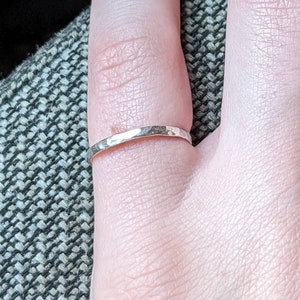 May include: A silver hammered ring on a finger.