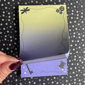 May include: A set of two purple and yellow sticky notes with a dragonfly, buttons, a key, and a spool of thread. The notes have a gradient design and the text "Fortuna Pins" is printed on the bottom of the note.
