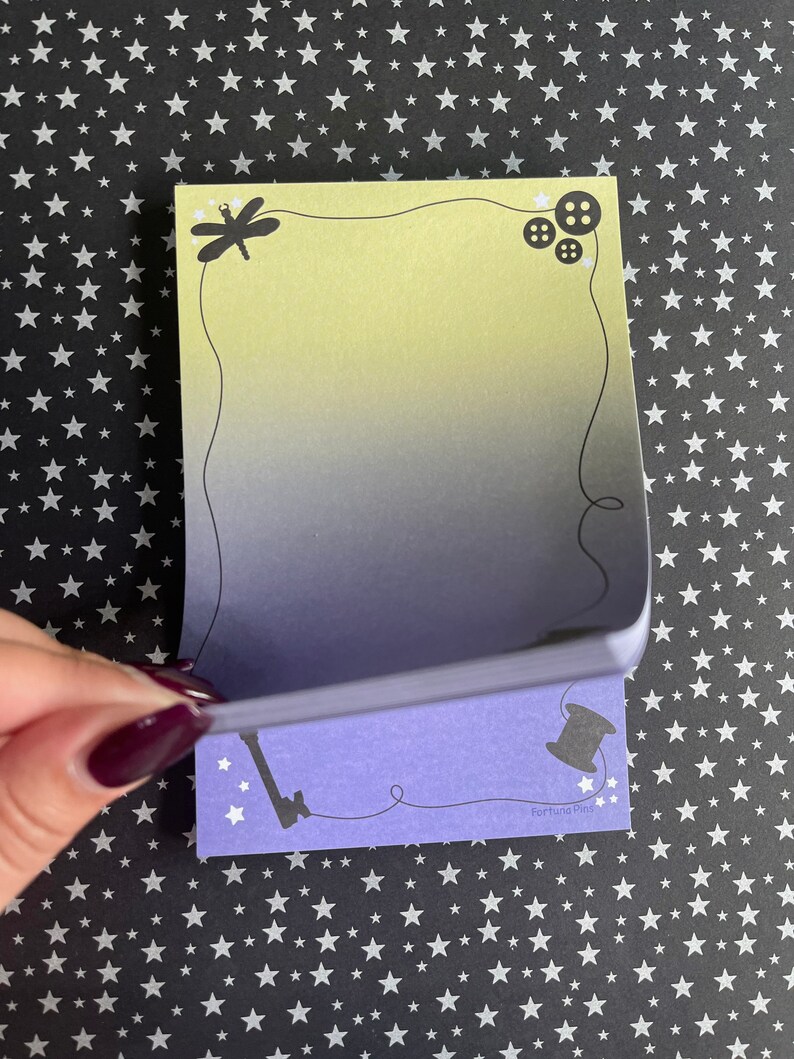 May include: A set of two purple and yellow sticky notes with a dragonfly, buttons, a key, and a spool of thread. The notes have a gradient design and the text "Fortuna Pins" is printed on the bottom of the note.