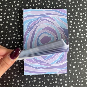 May include: A stack of purple and blue patterned memo pads with the text "Fortuna Pics" on the bottom right corner.